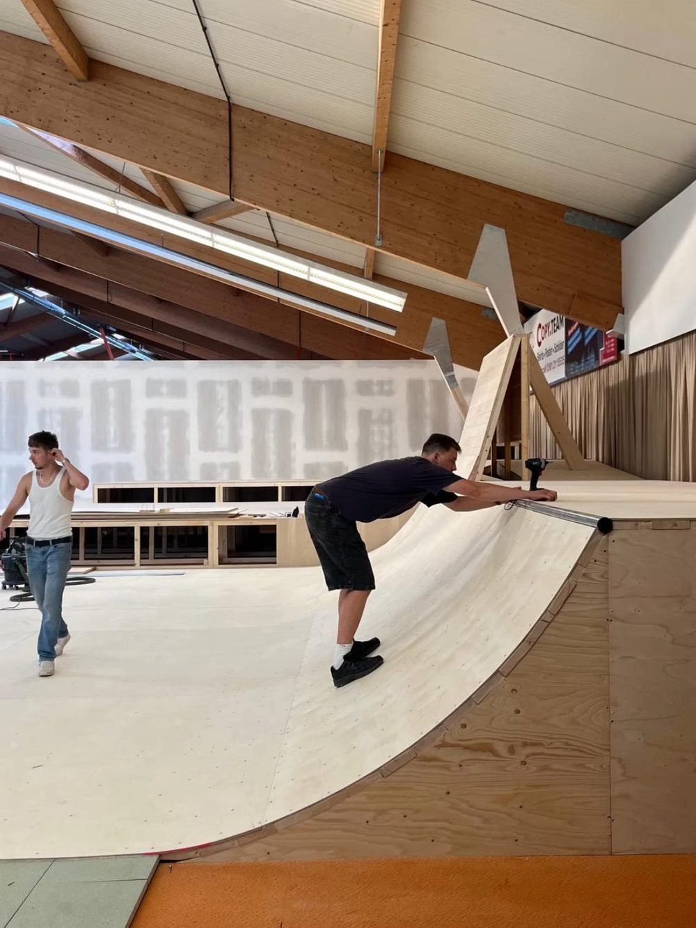 Ein Helfer montiert die Coping-Stange auf der fast fertigen Miniramp