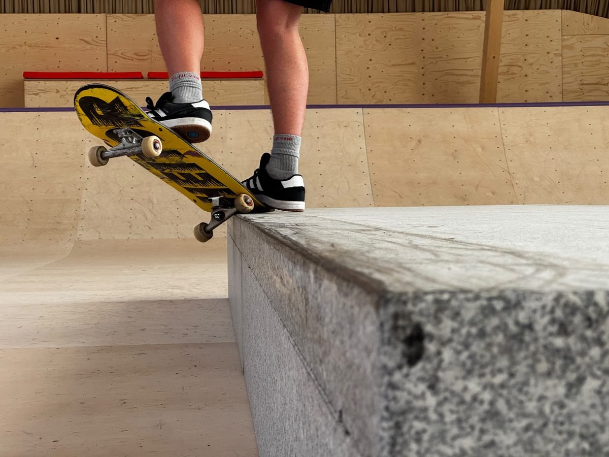 Skateboard an der Kante einer Granit-Ledge